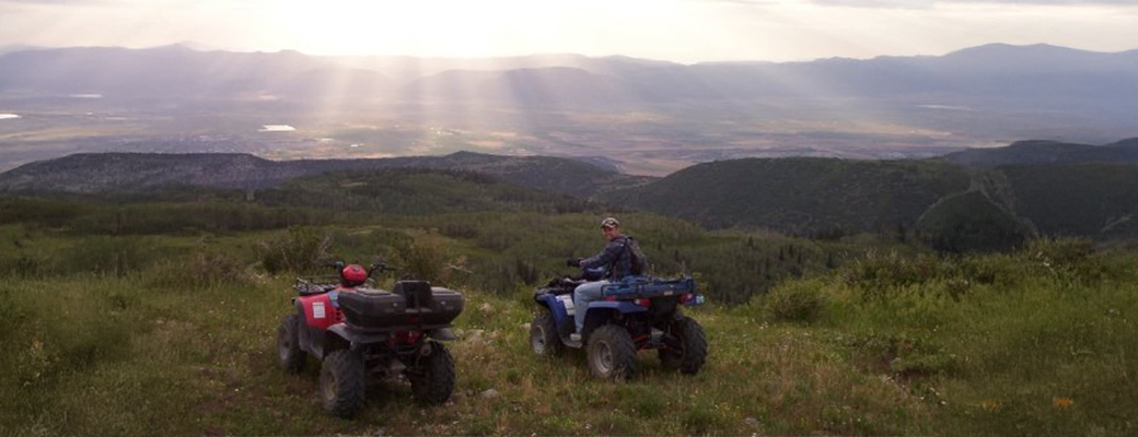 Image of Justin Osmond on a four wheeler outdoors beside another four wheeler